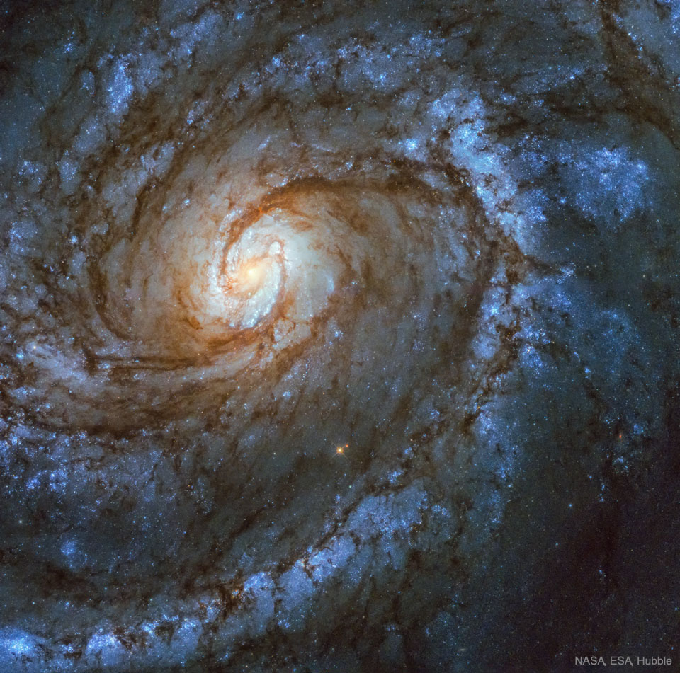 Na sliki je spiralna galaksija, v njenih spiralnih rokavih 
prevladujejo modre zvezde, v srediu je spiralna struktura, ki 
sama po sebi spominja na spiralno galaksijo. 
Ve informacij v pojasnilu.