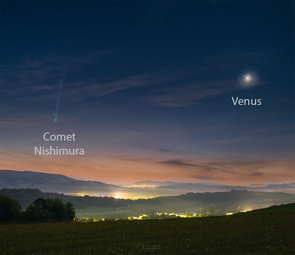A scenic and hilly landscape is shown just before sunrise.
On the left is Comet Nishimura near the horizon with a long tail
fading off toward the top of the frame. On the right is a bright spot
that is Venus. The sunrise sky is dark blue at the top but morphs
into tan at the horizon, while the foreground hills are green.
Please see the explanation for more detailed information.
