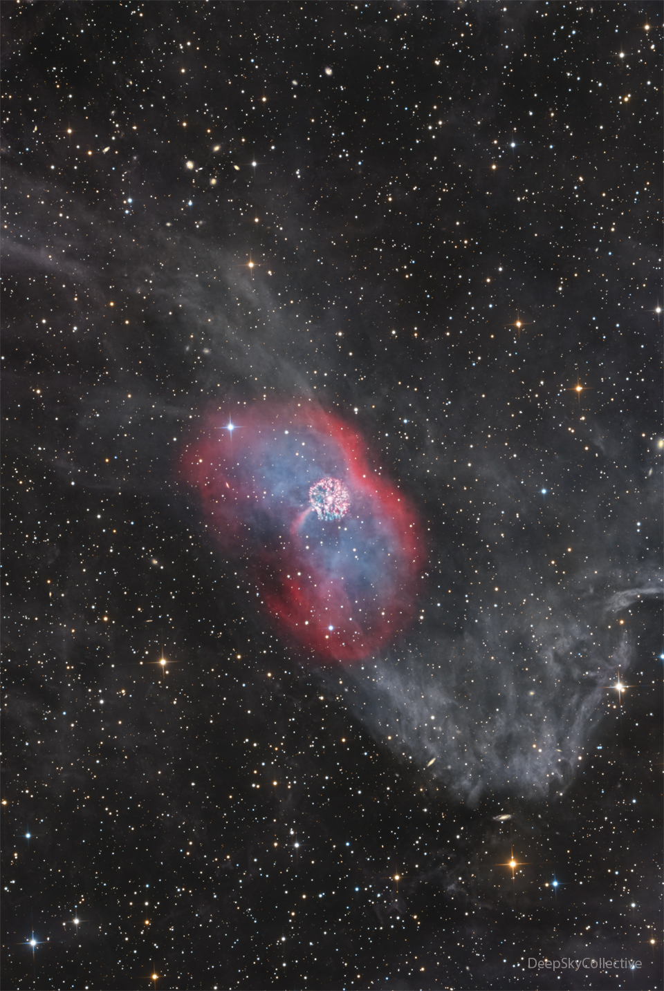 A faint nebula runs vertically in the image. In the
center is a red envelope surrounding diffuse blue emission.
In the center is a bright multicolored nebula that is
nearly circular.
Please see the explanation for more detailed information.