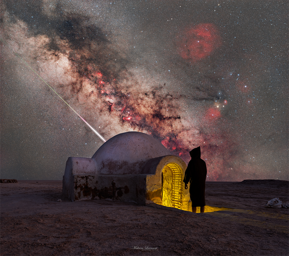 A starry sky is seen above a structure with an iconic
dome. A person in shadow stands at the entrance. Sloping down
in the sky is the central band of our Milky Way Galaxy. Just
below the Milky Way is the streak of a bright meteor.
Please see the explanation for more detailed information.