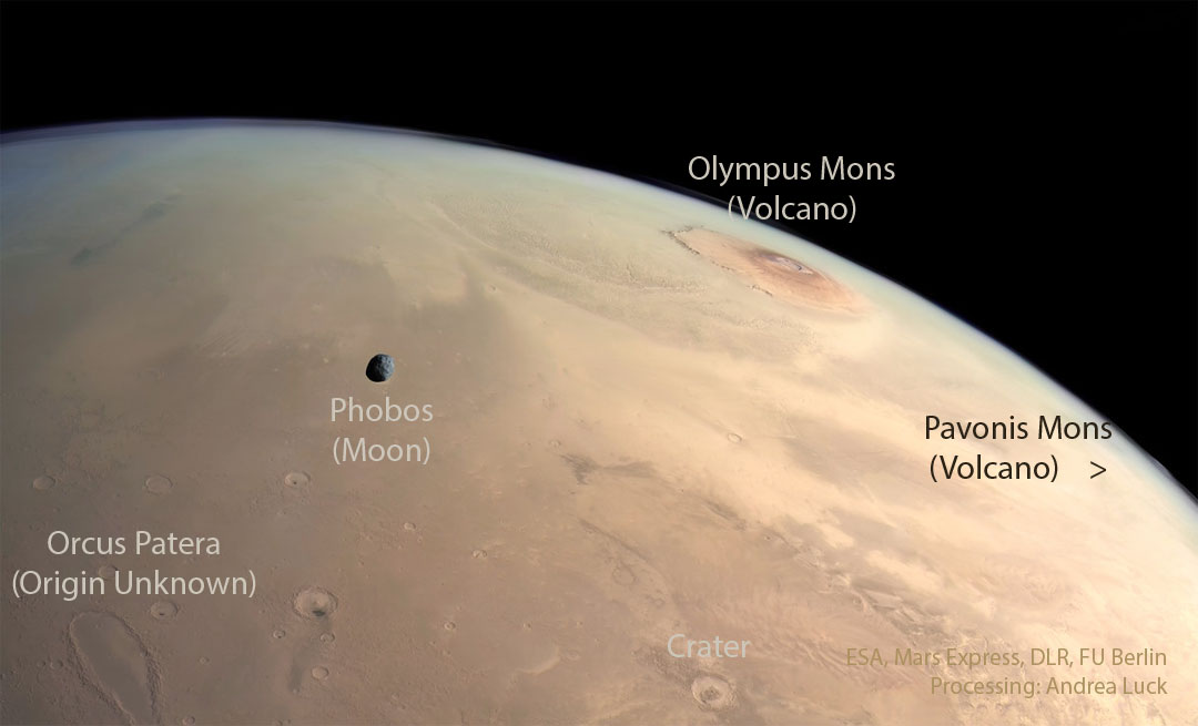 A panoramic view of the surface of Mars. Several landforms are
visible including craters and volcanos. A small dark moon is superposed
in front of part of the surface.
Please see the explanation for more detailed information.