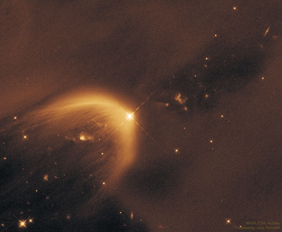 A starfield is dominated by light brown dust. In the
middle is a parabolic gas cloud opening toward the lower right.
A bright star is near the center at the apex of the parabolic
gas cloud.
Please see the explanation for more detailed information.