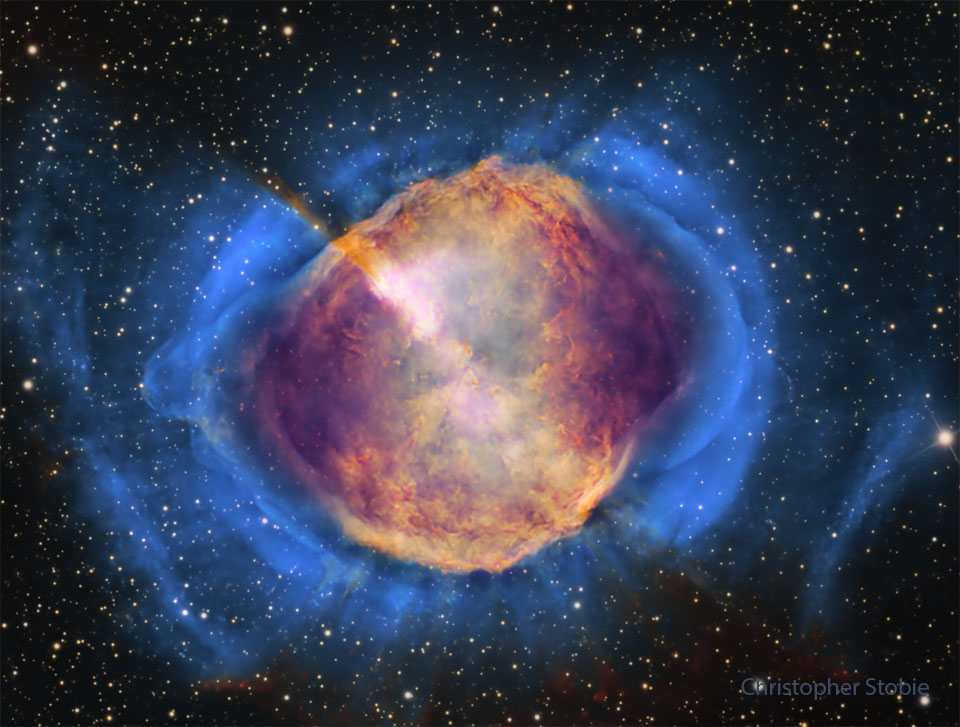 A starfield is shown with a frame dominated by a gaseous
nebula. The nebula, filled with structure, appears orange
in the center but blue
around the edges.
Please see the explanation for more detailed information.