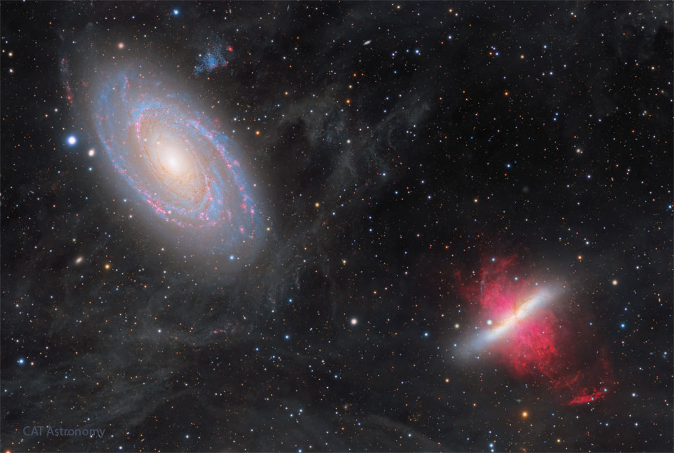 Two large galaxies are shown against a dark starfield.
The galaxy on the upper left has blue spiral arms speckled
with red nebulae. The galaxy on the lower right has a white
line with red filaments on each side. Thin wisps cover some
of the rest of the field.
Please see the explanation for more detailed information.