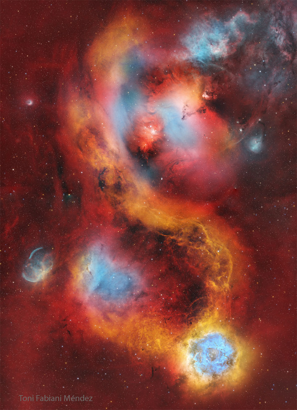 A starfield is covered with a light red glow. Several
nebulas are seen near the center. The famous Rosette nebula
appears in blue and white near the image bottom.
Please see the explanation for more detailed information.