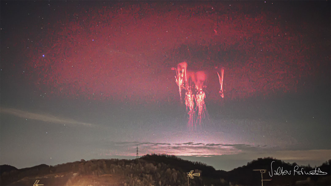 Trees on a hilltop are seen in a starry sky but with
clouds on the far horizon. A strange red circular band of
light is seen in the sky. Near this band's center, some
bright jellyfish like structures are visible.
Please see the explanation for more detailed information.