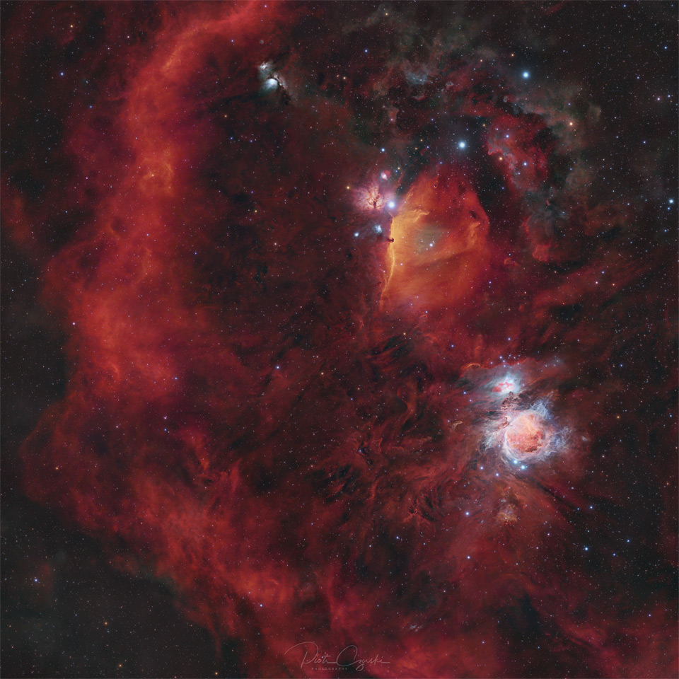 A starfield is shown filled with red glowing gas. On
the right is a blue-glowing complex nebula, while on the left
there is a long encircling arc of red gas.
Please see the explanation for more detailed information.