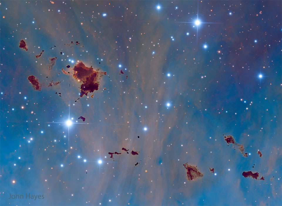 A starfield with a blue background shows several
unusual brown globs. They are generally irregularly
shaped.
Please see the explanation for more detailed information.