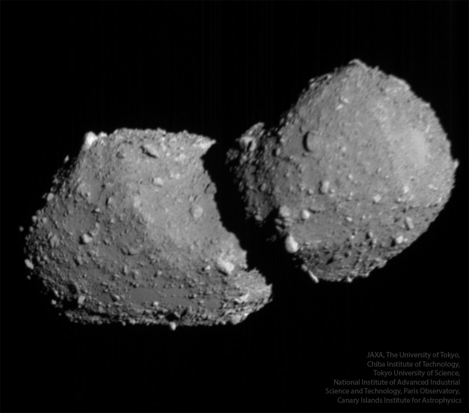 A large rocky object floats in dark space. The
object is gray and has many small protrusions.
Please see the explanation for more detailed information.