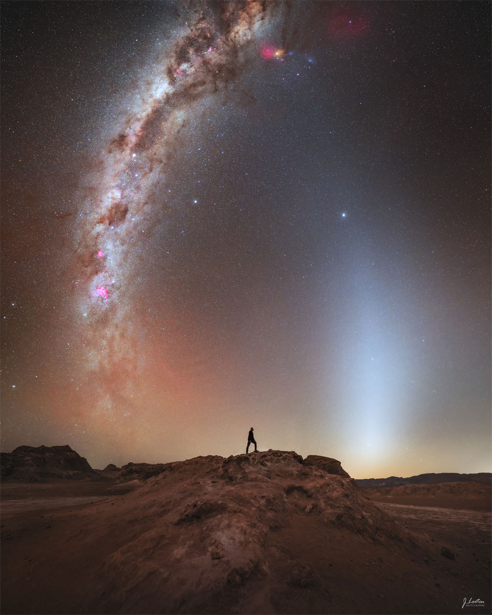 A distant person stands on a rocky landscape. Above is a
starry sky. Rising up from the horizon on either side of
the person are bright arching spires.
Please see the explanation for more detailed information.