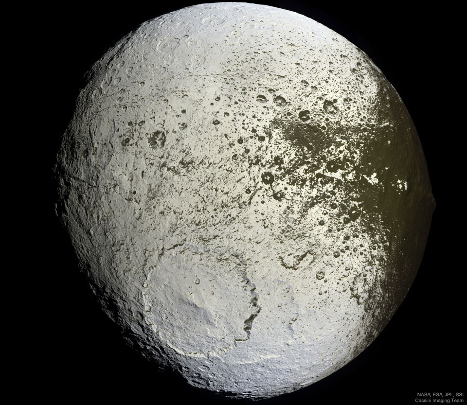 An unusually colored ball is shown against a
dark background. The ball has numerous craters but
a very large cratered near the lower center. Much of
the ball is light colored, but around the right and
top it is green-brown, with a border area that seems
splattered.
Please see the explanation for more detailed information.