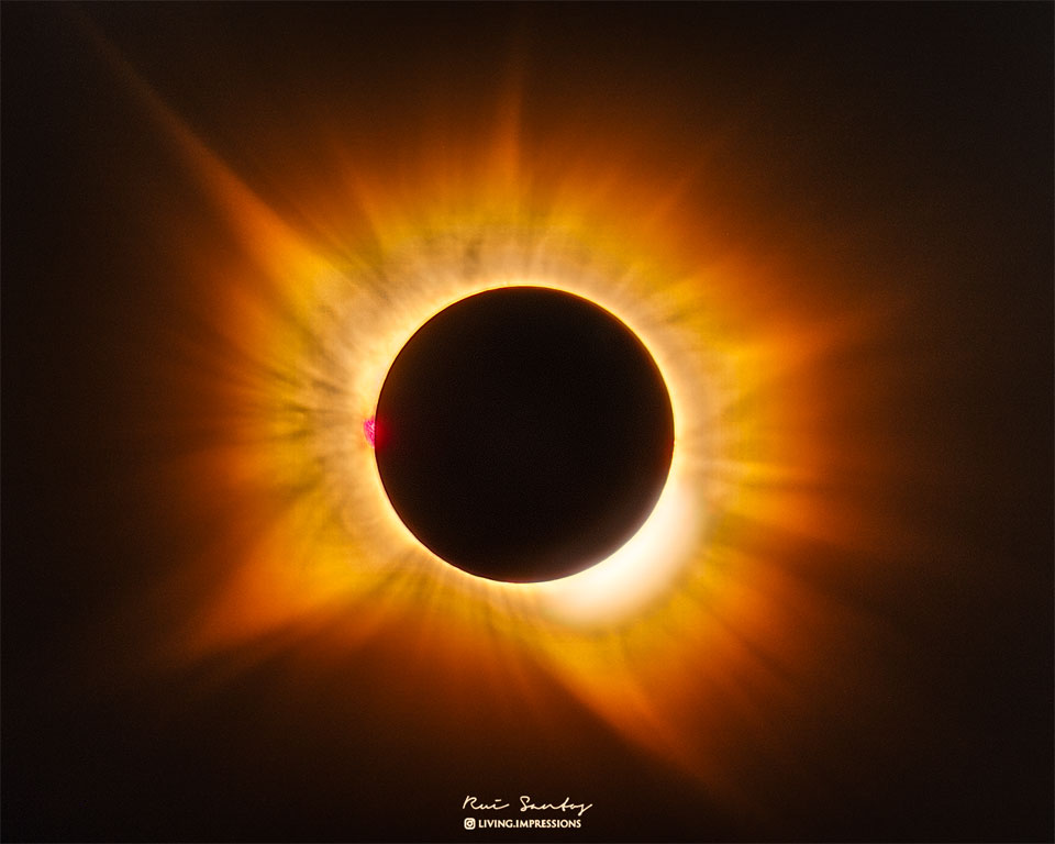 A total eclipse Sun is featured in the image center.
Around the Sun is a filamentary gold-hued corona flowing
out in all directions.
Please see the explanation for more detailed information.