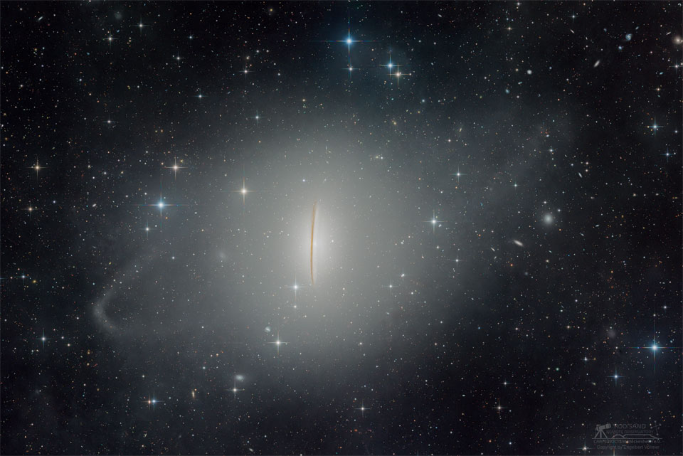 A starfield has an bright blobby mess in middle.
Running vertically through the very middle is a dark streak.
A diagonal ring of brightness surrounds the central blob.
Please see the explanation for more detailed information.